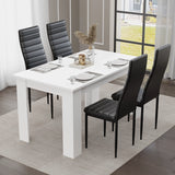 Modern white dining table set for four, paired with sleek black chairs. Styled in a contemporary dining room featuring elegant wall art and a statement chandelier — ideal for small families or compact spaces.