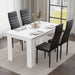 Modern white dining table set for four, paired with sleek black chairs. Styled in a contemporary dining room featuring elegant wall art and a statement chandelier — ideal for small families or compact spaces.