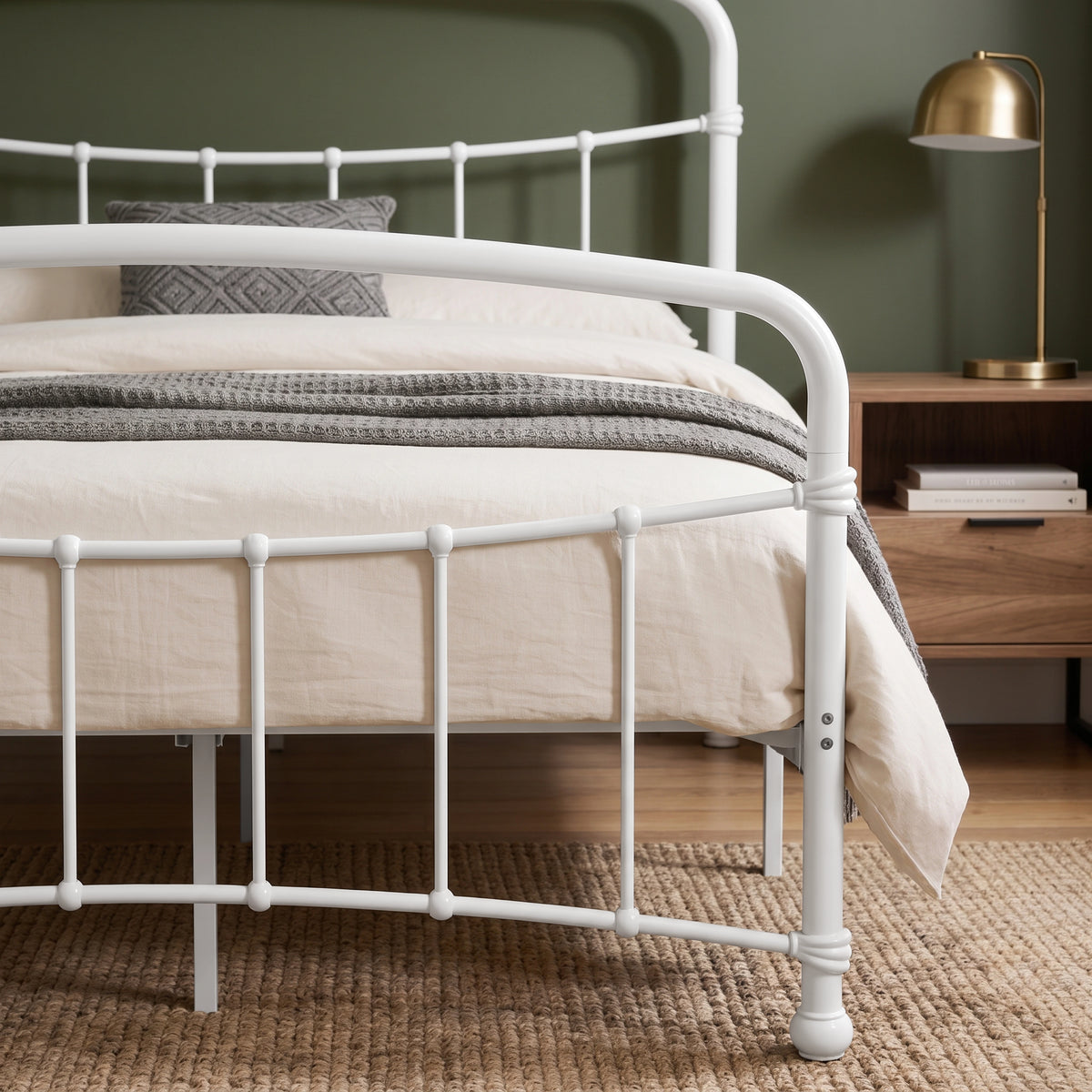 [White | Double] Footboard close-up showing curved rail, bars, rounded joints, bolts, bedding, knitted throw, and lamp.