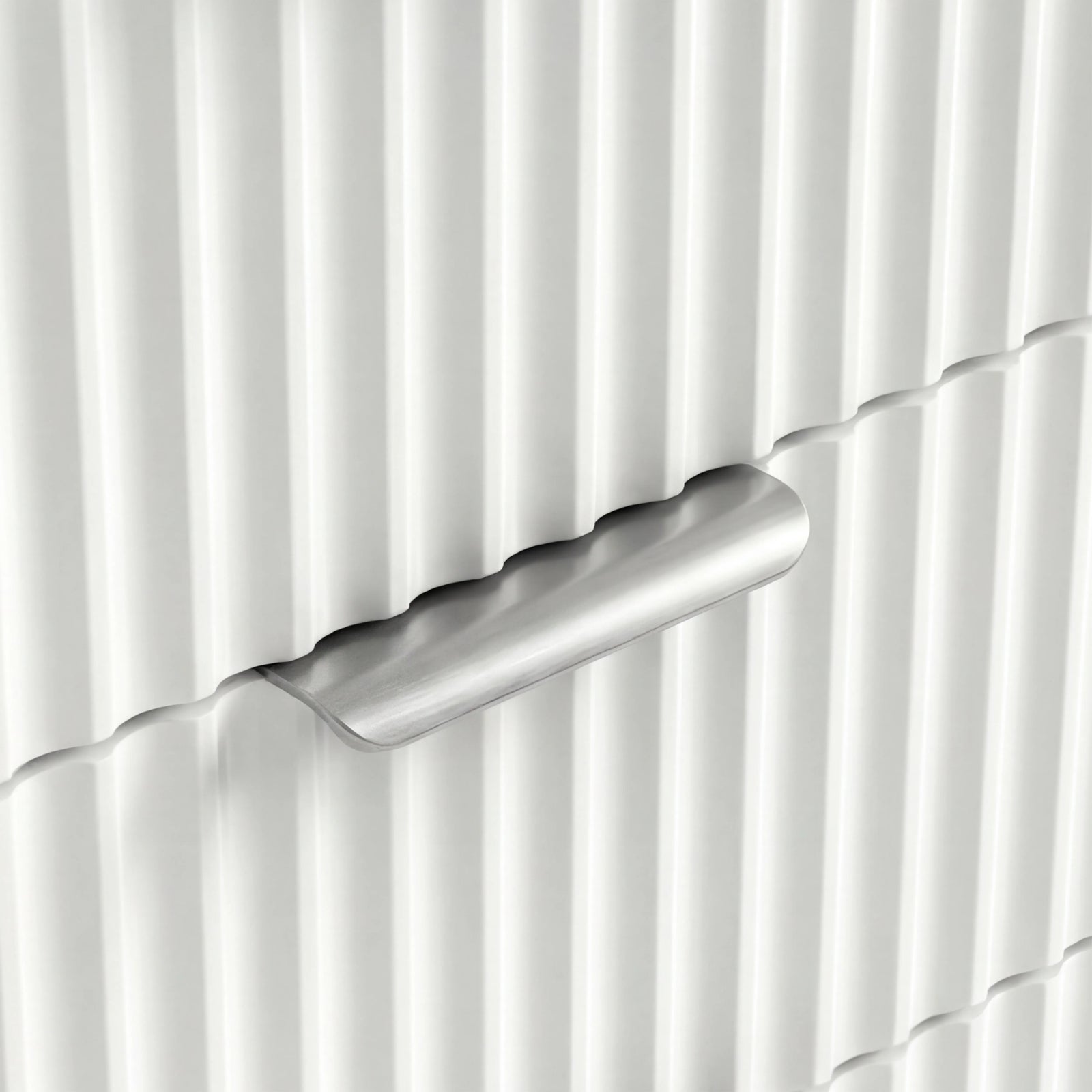 [White] Close view of silver metal handle on white flutrina front of chest of drawers in a natural light