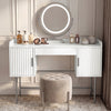 White dressing table with three drawers and a round mirror in flutrina design, placed against a wall in a softly lit room