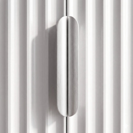 [White | 60cm] Flutrina close-up of the brushed silver handle centred between the white fluted door panels in daylight