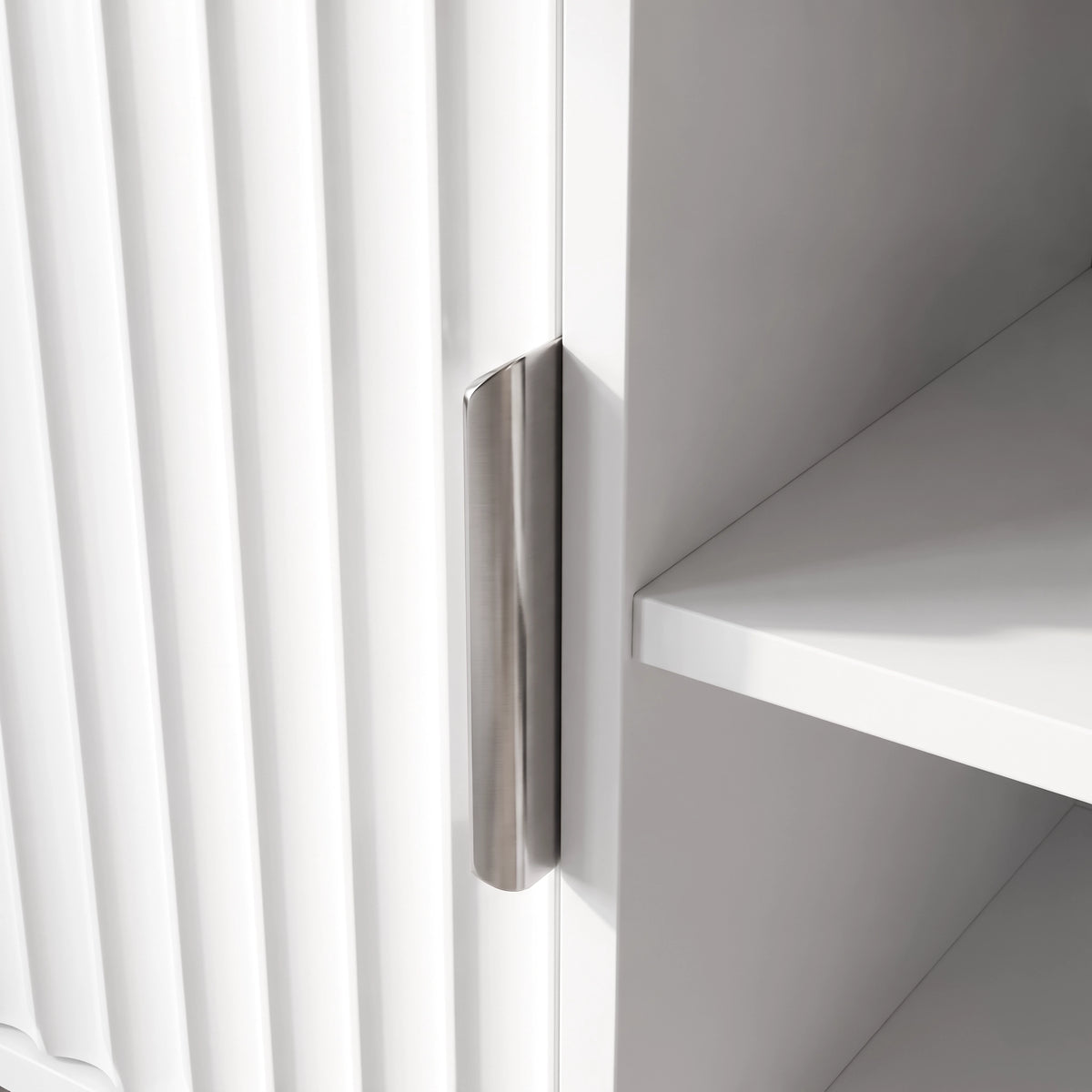 [White] Flutrina close-up showing fluted door grooves, brushed metal pull handle, and plain inner shelf edge.