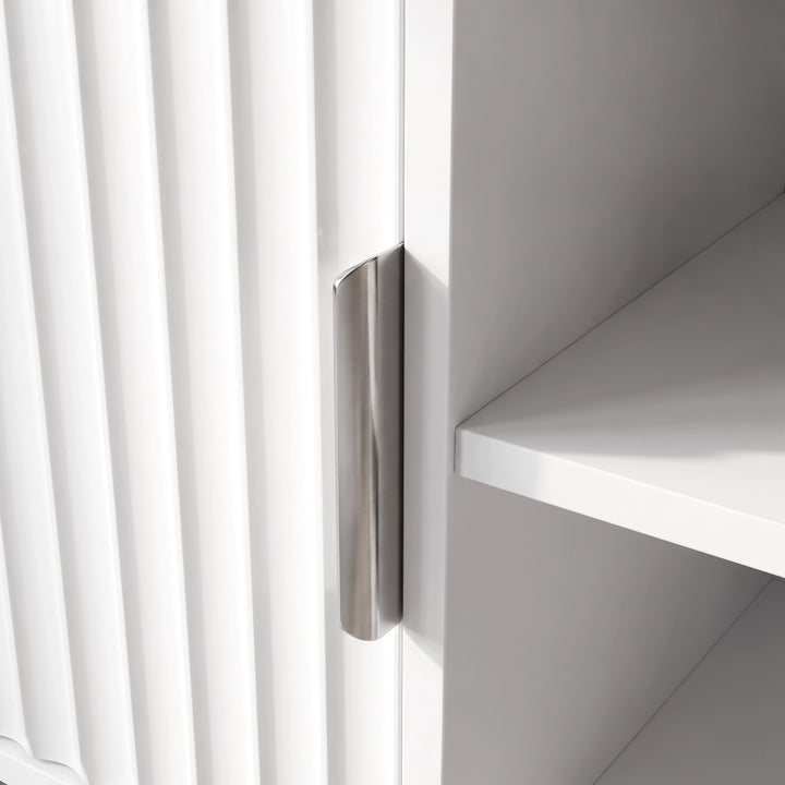 [White] Flutrina close-up showing fluted door grooves, brushed metal pull handle, and plain inner shelf edge.