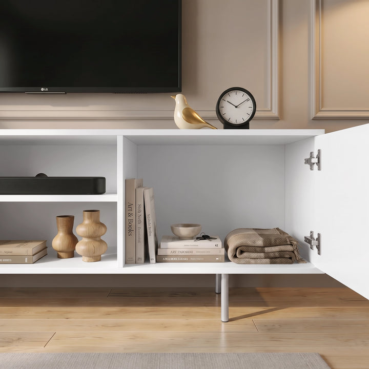 [White] Flutrina TV unit open cabinet detail showing shelves, hinge hardware, books, folded throw, soundbar, and ornament.