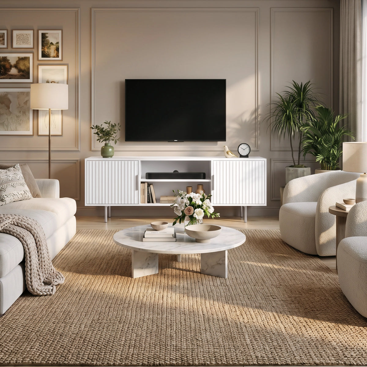 [White] Flutrina TV unit in living room with wall TV, fluted doors, shelves, sofa, chairs, coffee table, rug, and art.