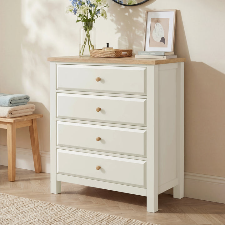 [White] Haven 4 drawer chest with oak top and round oak knobs shown at a three-quarter angle in a warm neutral bedroom