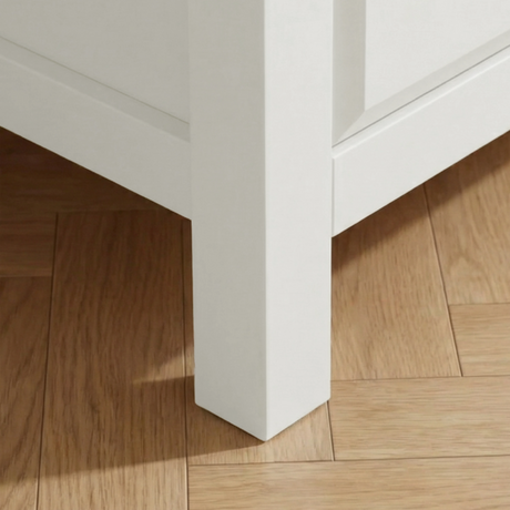 [White] Haven chest close-up of the solid square white painted leg resting on warm oak herringbone parquet flooring