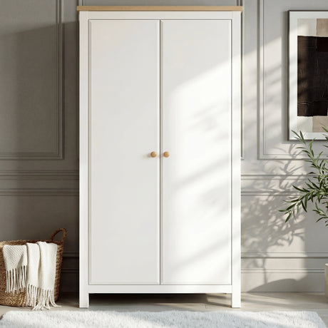 [White] Haven modern two-door  wardrobe with oak top and round knobs in a sunlit minimalist bedroom.