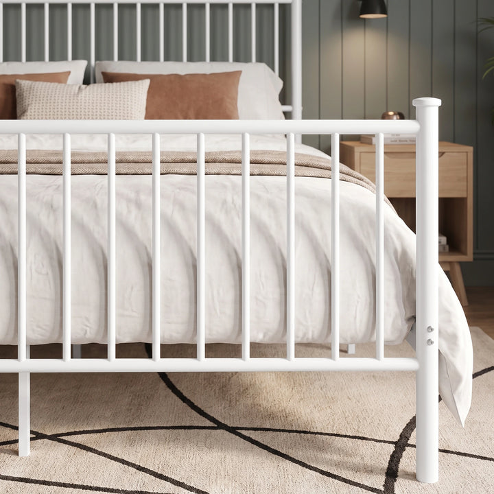 [White | King] Footboard close-up showing vertical bars, a capped post, fixing bolts, centre leg, and bedding behind.