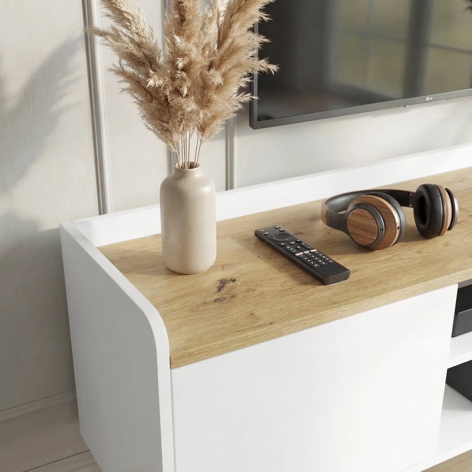 [White | 112 cm] Larvik close-up of oak top surface with pampas grass vase, remote control, headphones, and smooth white curved side edge