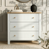 [White] Linra 3-drawer chest of drawers in a lifestyle bedroom setting with mirror and vase on oak top