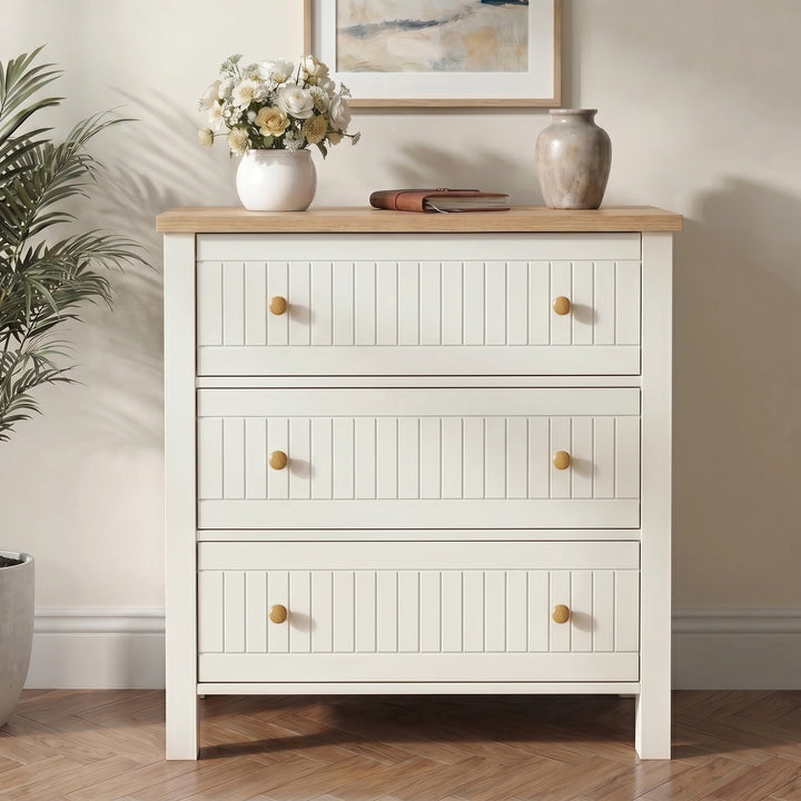 [White] dresser with wooden top in a room with a plant and framed picture