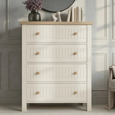 [White] Linra 4 drawer chest front view with oak top styled with dried floral vase, sculptural ornament, and books below a round black mirror
