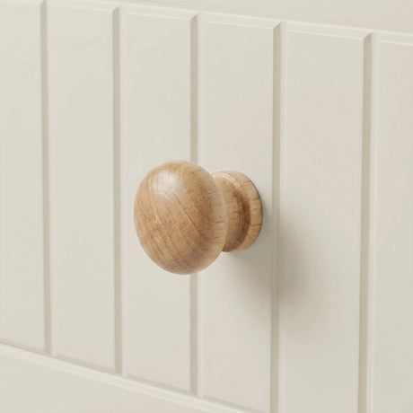 [White] Linra 4 drawer chest macro close-up of a single rounded solid wood drawer knob set against painted tongue-and-groove panel surface