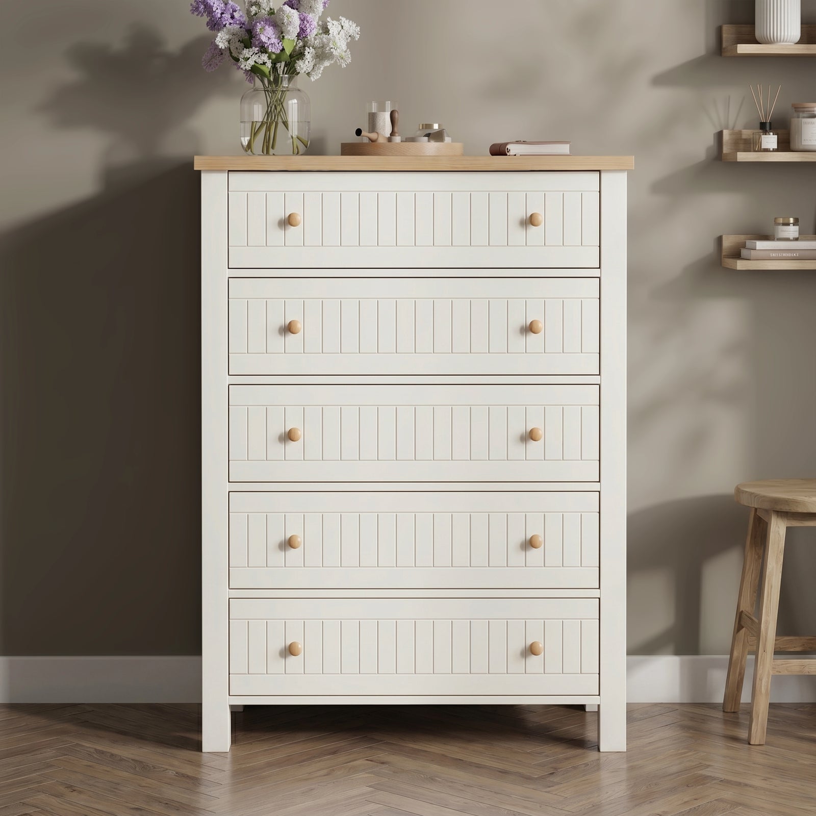 [White] Linra tall 5 drawer chest front view against dark wall with oak top styled with pale vase, dried palm, and brass candle tray