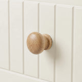 [White] Linra tall 5 drawer chest macro close-up of a single rounded solid wood drawer knob against painted tongue-and-groove panel surface