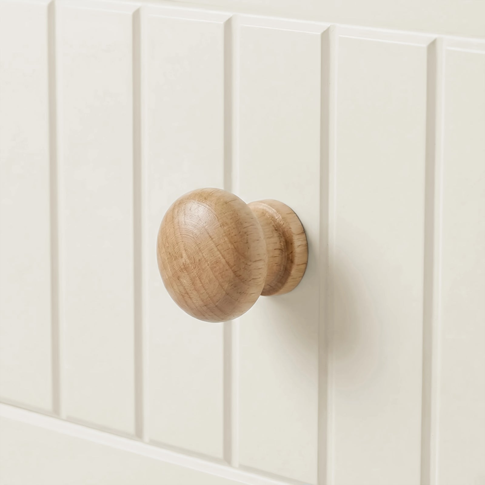 [White] Linra tall 5 drawer chest macro close-up of a single rounded solid wood drawer knob against painted tongue-and-groove panel surface