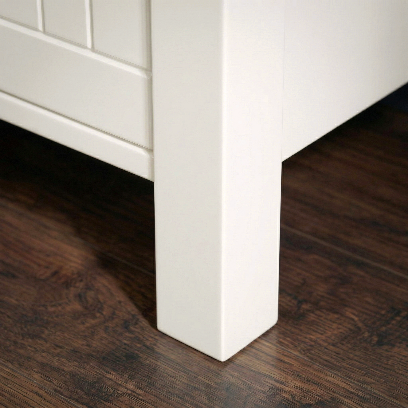 [White] Linra tall 5 drawer chest close-up of solid square painted leg construction and raised base clearance on dark hardwood flooring
