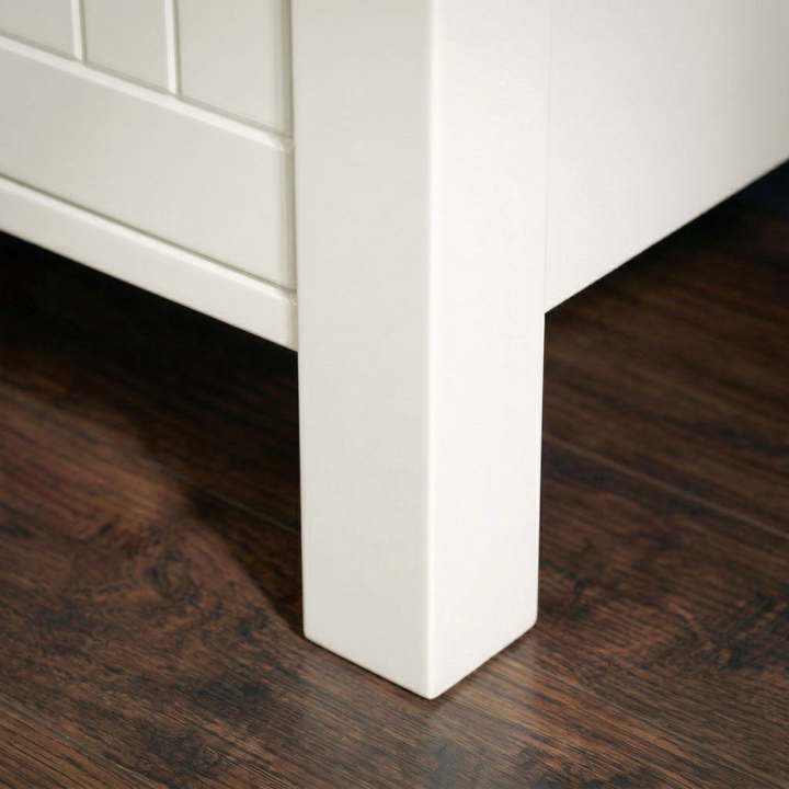 [White] Linra tall 5 drawer chest close-up of solid square painted leg construction and raised base clearance on dark hardwood flooring