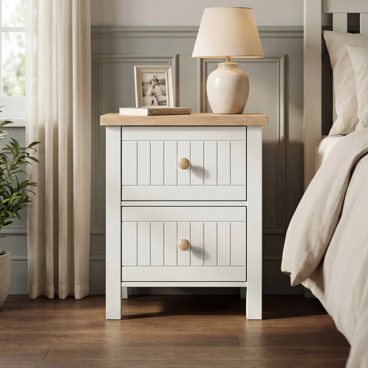 [White] Linra 2-drawer bedside table in a bedroom lifestyle setting with vase and decorative items on oak top