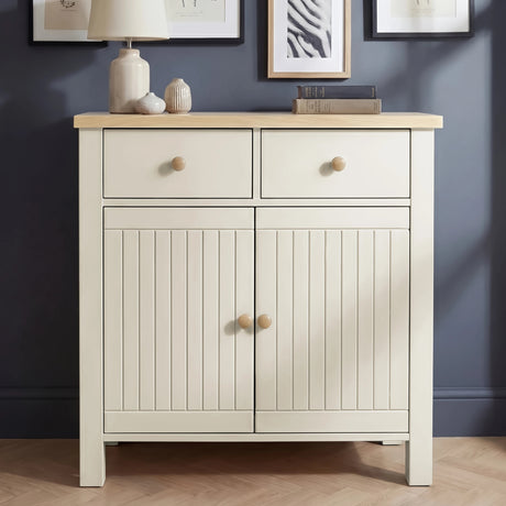 [White] Linra sideboard front view with oak top surface styled with stacked books, botanical print, and pampas grass vase in natural light