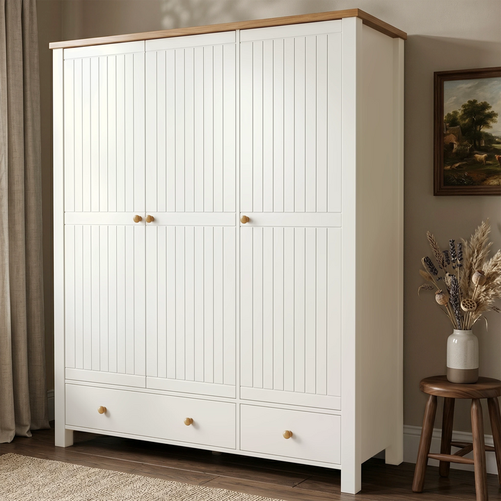 [White] Linra wardrobe angled closed view with beaded doors, lower drawers, oak top, curtain, framed art, vase, and stool.