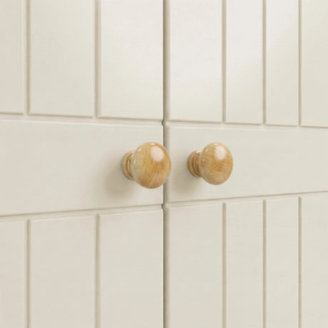 [White] Linra 2 door wardrobe macro close-up of two rounded solid wood door knobs set against painted tongue-and-groove panel surface