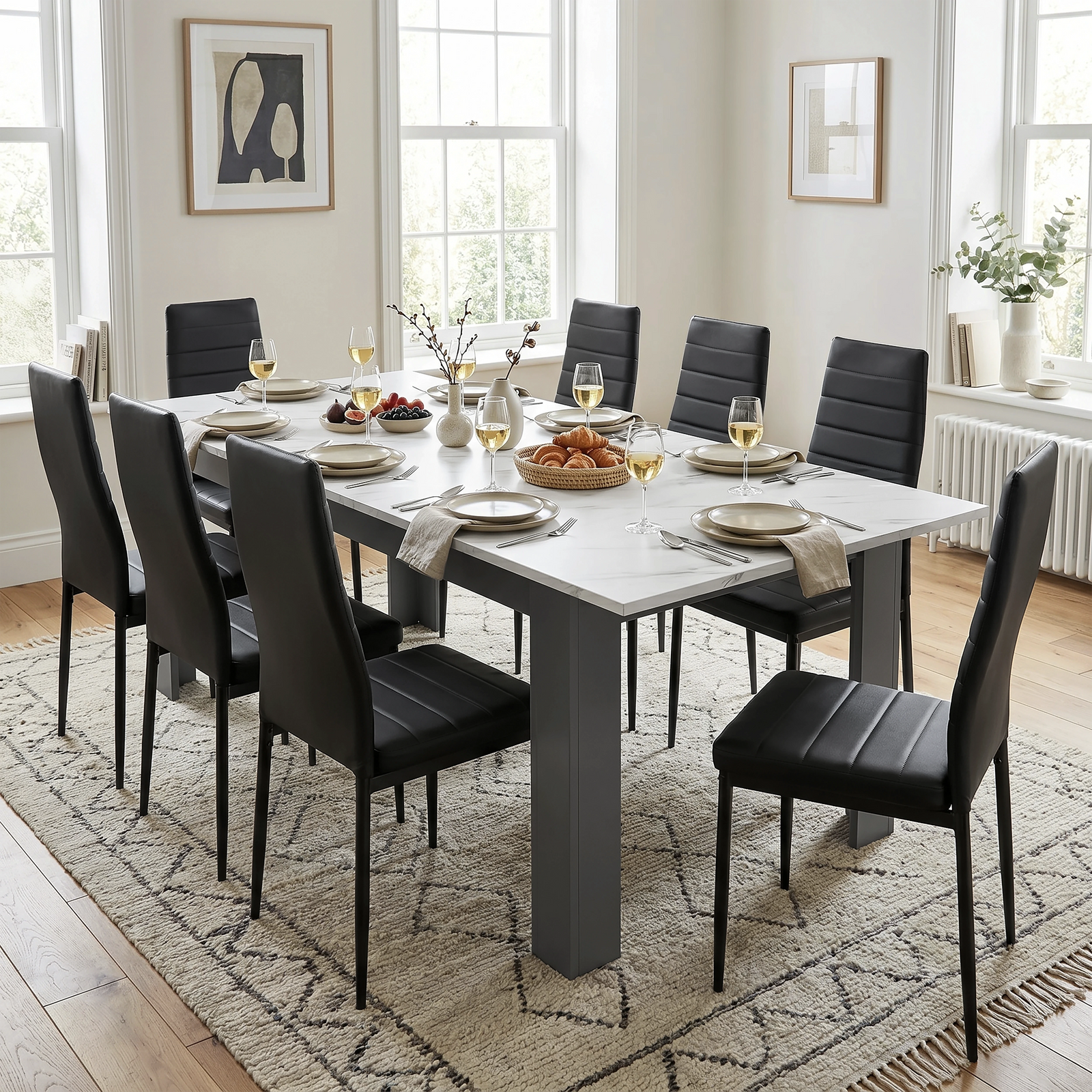[White Marble] Extended marble-effect dining table for 6-8 at breakfast; eight black chairs surround its thick grey legs.