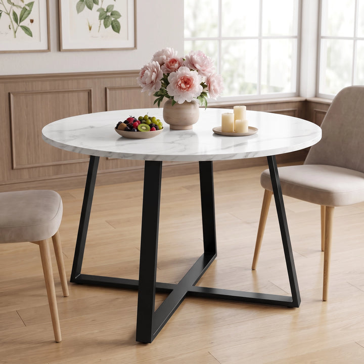 [White Marble] Round dining table in a bright room with flowers, fruit and candles on top between two beige chairs.