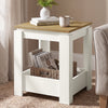 [White] Square side table beside a sofa, with a wicker basket and books in the open lower storage