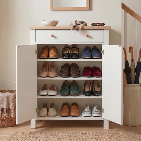 [White] Both doors fully open showing 4 shelves loaded with 12 pairs of flat shoes and loafers, umbrella stand right, woven basket left