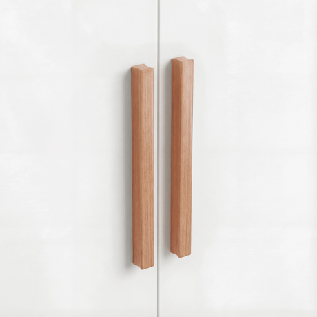 Close view of natural wood vertical handles mounted on white double wardrobe with drawers