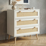 [White] Rattan three-drawer chest shown at an angle, styled with dried botanicals and gold geometric decor on top