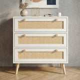 [White] Rattan three-drawer chest photographed straight-on, showing dual wooden knobs and full rattan panel detail