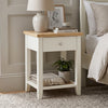 [White] Angled view of the White Shaker Bedside Table with natural oak top, single drawer, and open shelf.