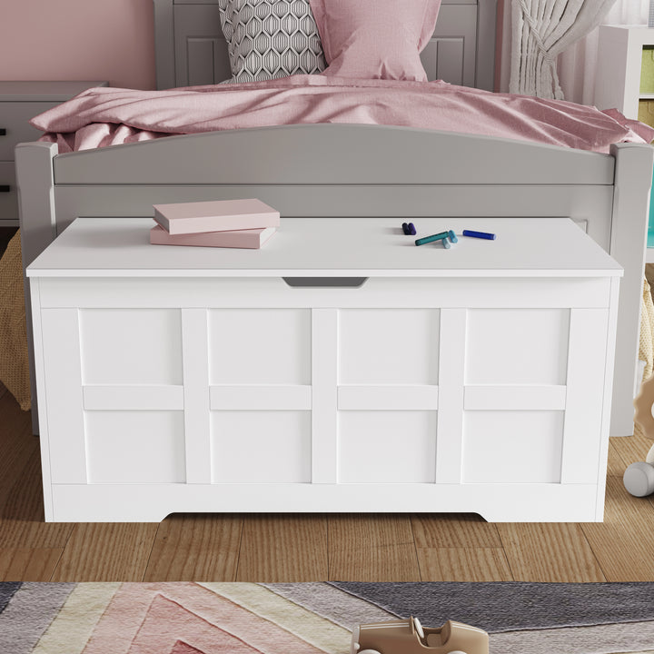 [White] White shaker storage chest closed at the foot of a grey bed, pink notebook and felt-tip pens resting on the flat lid
