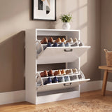 [White] two-tier shoe organizer with pull-out shoe racks, shown in a styled room setting with a beige wall, wooden floor, and a small plant on top.