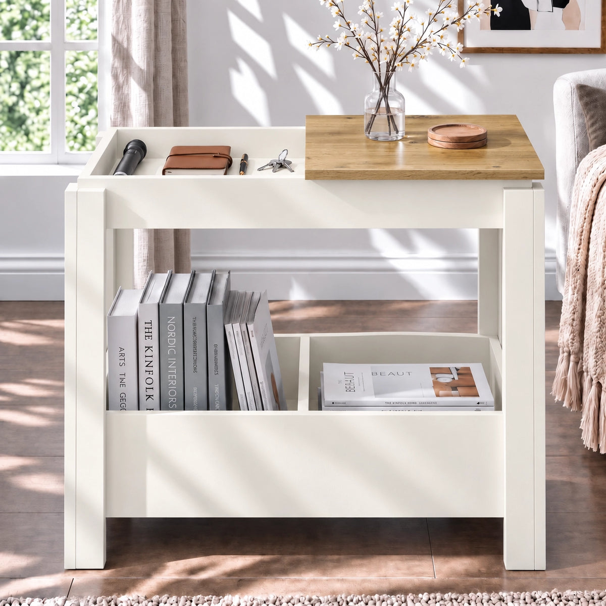 [White] Front view of an open side table compartment holding small items, with a blossom vase above and books underneath.