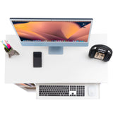 top view of a cheap computer desk in white showing an extended tray, monitor, phone, and accessories for budget home offices