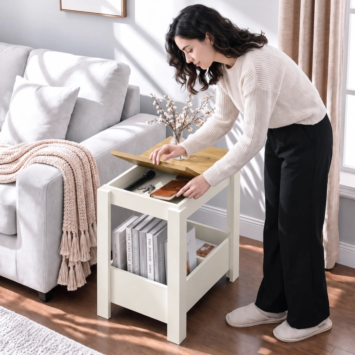 [White] A woman lifts a tabletop panel and reaches into the storage beside a sofa, with upright books in the lower section.