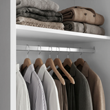 [White] Torvek wardrobe interior close-up of chrome hanging rail with shirts and upper shelf with folded knits