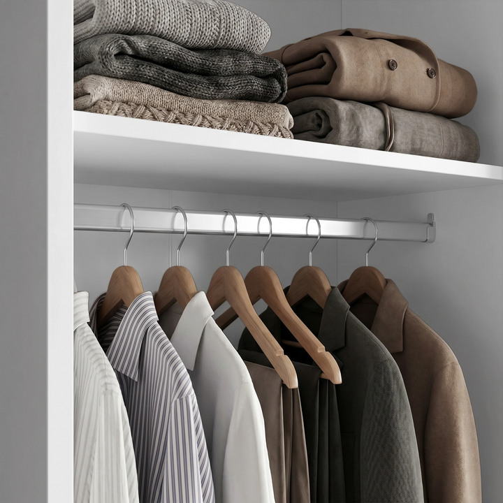 [White] Torvek wardrobe interior close-up of chrome hanging rail with shirts and upper shelf with folded knits