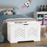 White toy storage with geometric design in a child's bedroom with toys and a teddy bear.