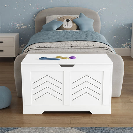 White toy storage bench in a child's bedroom with a bed and teddy bear in the background.