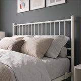 [White | Double] Metal bed close-up view of tall white bar headboard, layered neutral pillows, side rail and mattress stop.