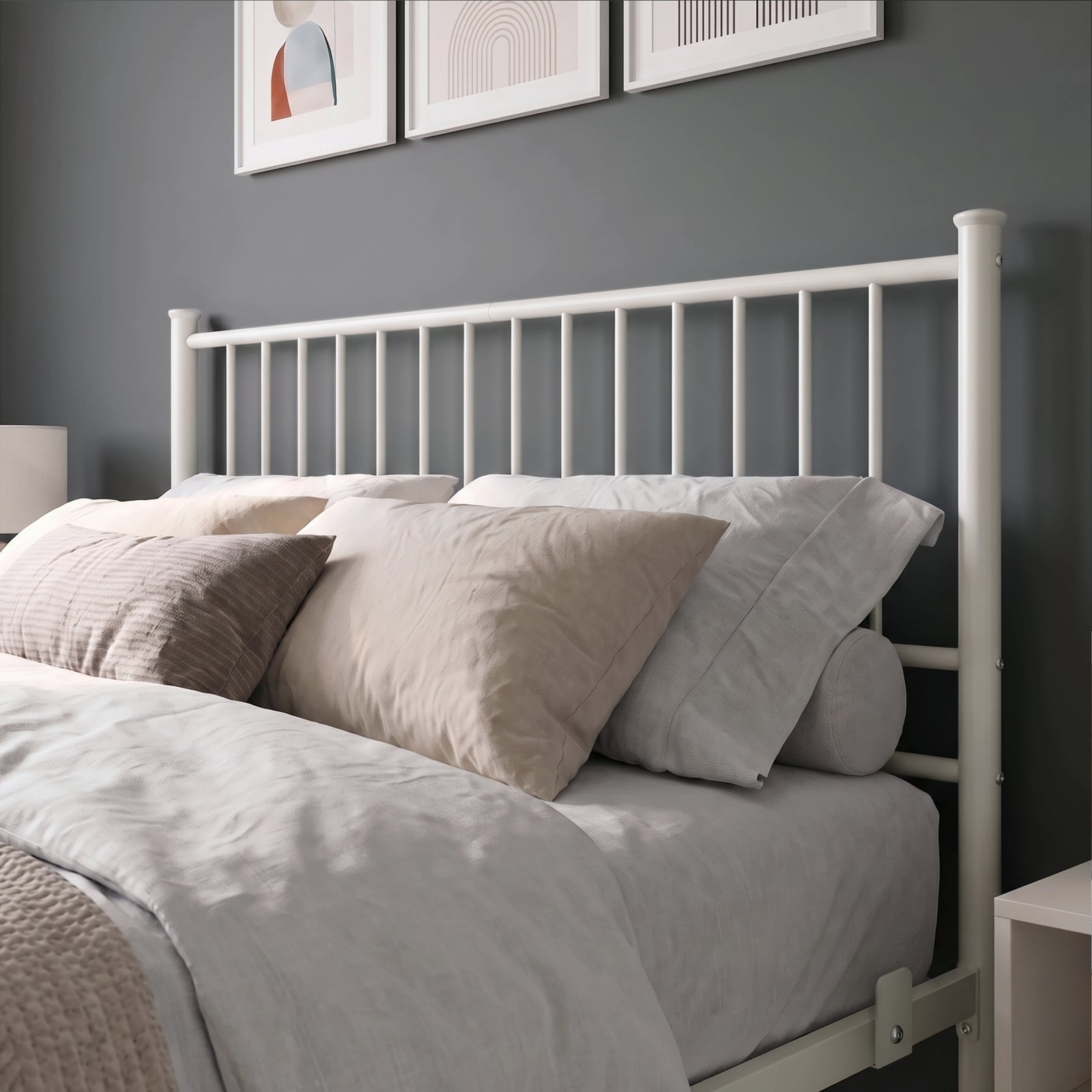 [White | Double] Metal bed close-up view of tall white bar headboard, layered neutral pillows, side rail and mattress stop.