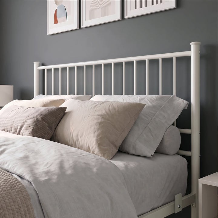 [White | Double] Metal bed close-up view of tall white bar headboard, layered neutral pillows, side rail and mattress stop.