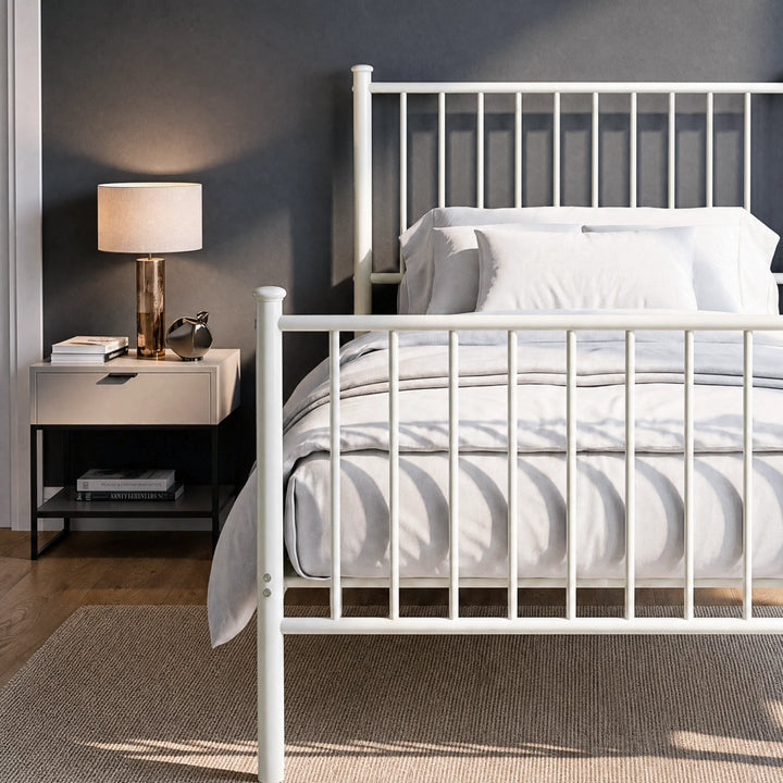 [White | Single] Metal bed close up view of bar headboard and footboard, white-grey bedding, lamp, books and silver decor.