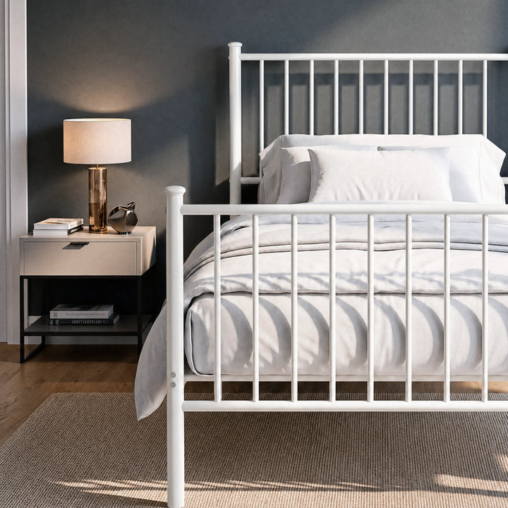 [White | Single] Metal bed close up view of bar headboard and footboard, white-grey bedding, lamp, books and silver decor.